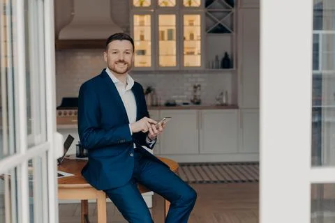 Bearded guy entrepreneur in suit using modern gadgets in his apartment Stock Photos