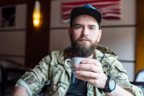 A bearded guy. A guy with a cup of coffee in no focus. Stock Photos