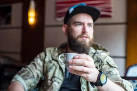 A bearded guy. A guy with a cup of coffee in no focus. Foto stock