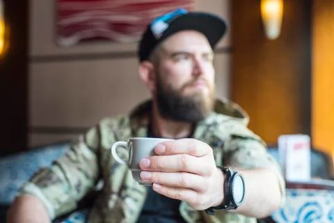 A bearded guy. A guy with a cup of coffee in no focus. Stock Photos