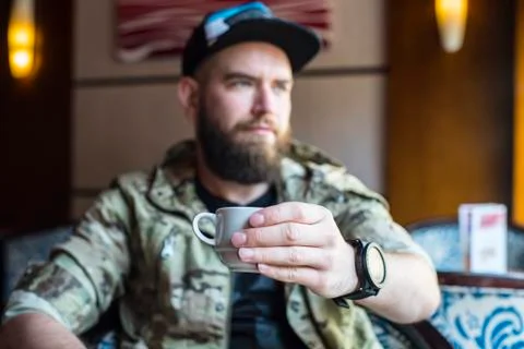 A bearded guy. A guy with a cup of coffee in no focus. Stock Photos
