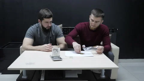 Bearded guy puts weed into plastic bottle bong at table Stock Footage 145714236
