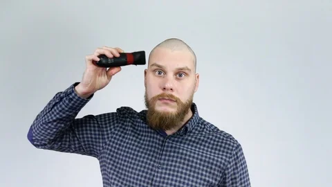 Bearded guy shaves his head with hair clippers.Looking in the reflection. Stock Footage 122012354