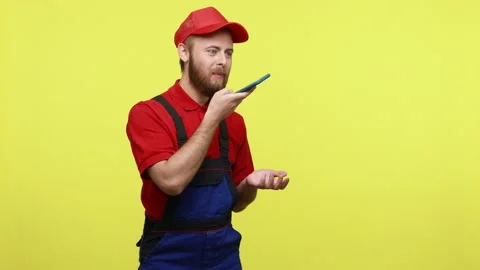 Bearded handyman using smart phone, recording command or voice message to Stock Footage 161437177