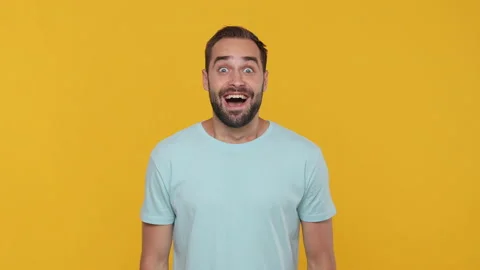 Bearded happy young man 20s in basic casual blue t-shirt looking shocked Stock Footage 148286777