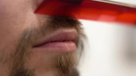 A bearded hipster combs a mustache with a comb Foto stock