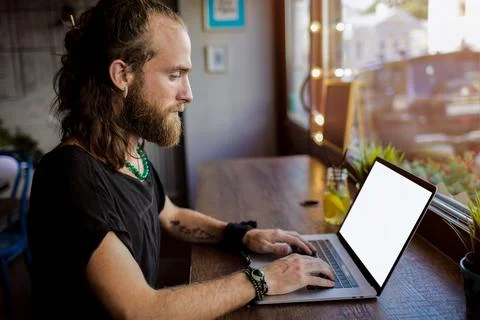 Bearded hipster guy creative web content writer keyboarding on laptop compute Stock Photos