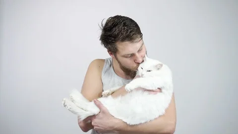 Bearded hipster guy holding a big beautiful white cat in hands 動画素材 121688239