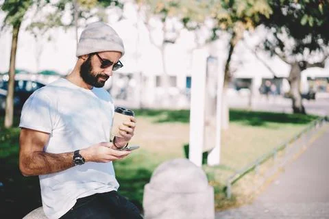 Bearded hipster guy in winter hat browsing content and writing mail message via Stock Photos