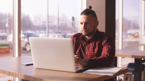 Bearded hipster working at a laptop in a cafe Stock Footage 87186724