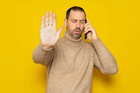 Bearded hispanic man in a turtleneck asking not to be disturbed while talki.. Stock Photos