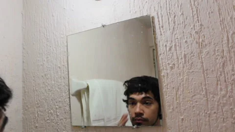 Bearded Hispanic young man looking at his face in the bathroom mirror Stock-Footage 132525047