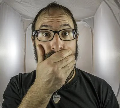 A bearded horrified looking man with black glasses Stock Photos