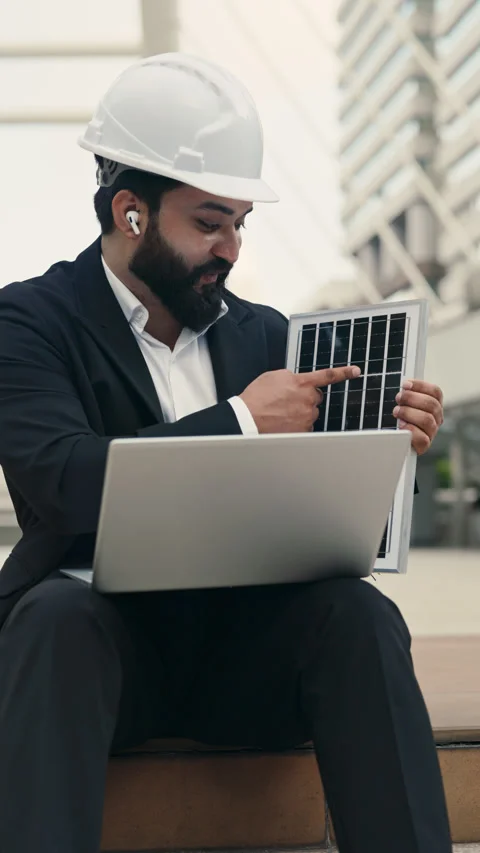 Bearded Indian engineer in helmet demonstrating solar panel on video call Stock Footage 313619159