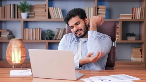 Bearded Indian man experiences acute elbow pain while working on laptop. Video stock 237989442
