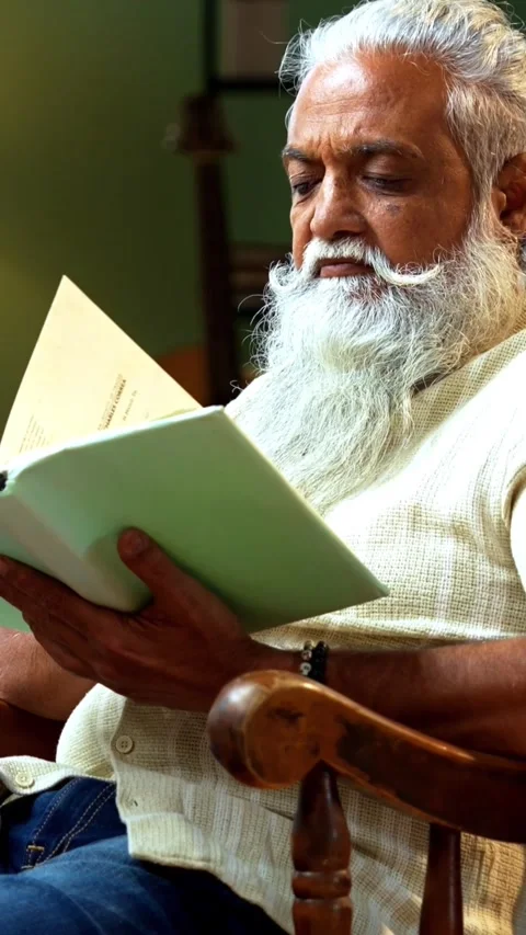 Bearded Indian reader engrossed in printed literature during free time indoors Video stock 342756977