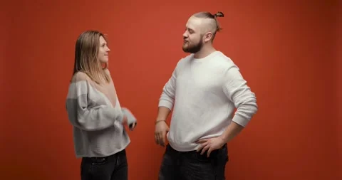 Bearded macho man demonstrating his muscles power to young woman on red Stock Footage 149036895