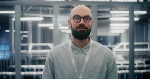 Bearded Male IT Engineer With Glasses, Smiling Confidently While Adjusting Stock Footage 325421894