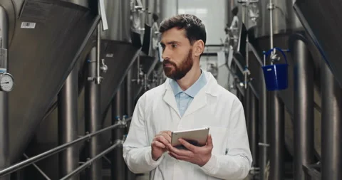 Bearded male process engineer entering data on tablet at brewery. Handsome man Stock Footage 131296864