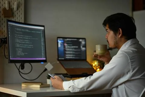 Bearded male software developer drinking coffee and coding at home office 스톡 사진