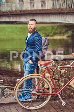 Bearded male with a stylish haircut dressed in casual clothes with a backpack Stock Photos