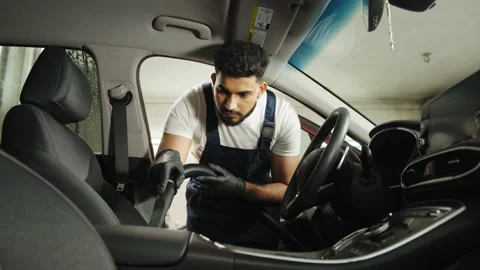 Bearded male worker making cleaning process with a vacuum cleaner, releasing car Stock Footage 233989189