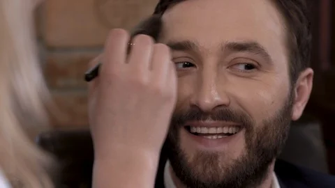 Bearded man actor is smiling while getting makeup before filming. Stock Footage 89043653