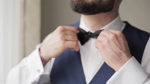 Bearded man adjusts black bowtie closeup hurrying get ready for formal party Stock Footage 87009808