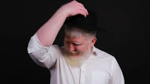 Bearded man with albinism putting a hat on, isolated on black background. Stock Footage 143336053