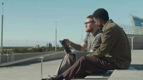 Bearded Man and Curly-Haired African American Man Discussing Work on Laptop Stock Footage 303633160