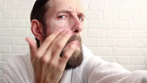 Bearded man applying moisturizer cream on face skin care concept  close up Stock Footage 151640095