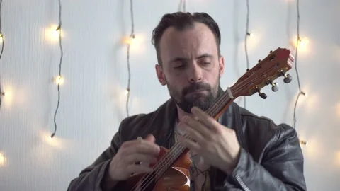 A bearded man are playing the 6-strings ukulele Stock Footage 170087436