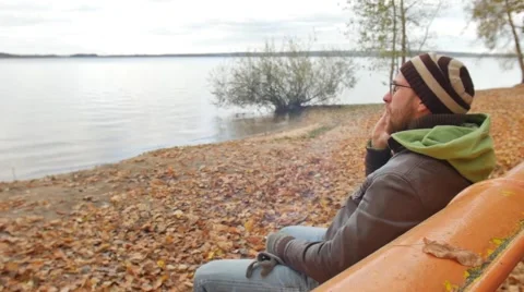 A bearded man in the autumn on a bench talking on a cell phone agrees and nods Stock Footage 68971202