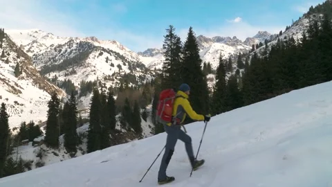 A bearded man with a backpack actively goes up in the mountains in winter Stock Footage 233987426
