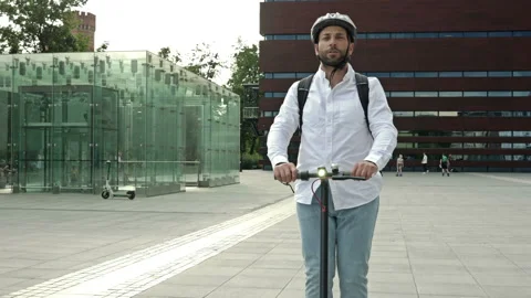 Bearded man with a backpack and in a protective helmet rides an electric scooter Stock Footage 228679630
