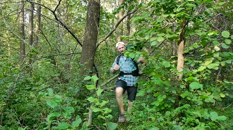 A bearded man with a backpack bursting through the bushes Stock Footage 65482857