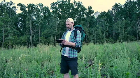 Bearded man with backpack looking at a map of the tablet Stock Footage 65484358