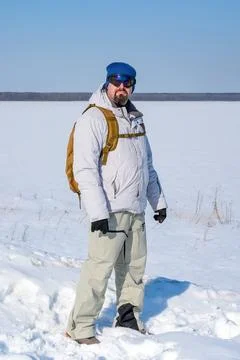 Bearded man with backpack standing alone in snowy winter landscape, enjoyin.. Stock Photos