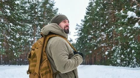 Bearded man with backpack standing in snowy pine forest during winter hike,.. Stock Photos