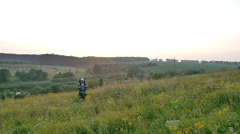A bearded man with a backpack walking in the field. Sunset Stock Footage 67425468
