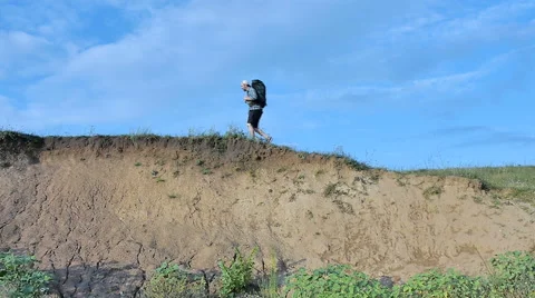 A bearded man with a backpack walks along the cliff Stock Footage 65482864