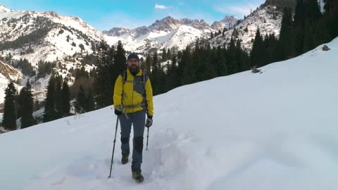 A bearded man with a backpack walks along a trail in the winter in the mountains Vidéo 233987673