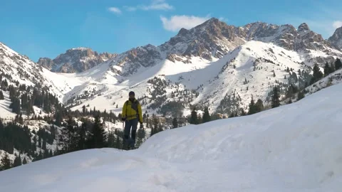 A bearded man with a backpack walks along a trail in the winter in the mountains Stock Footage 233988160