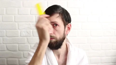 Bearded man in bathrobe combing his wet hair after shower close up Stock Footage 150344605