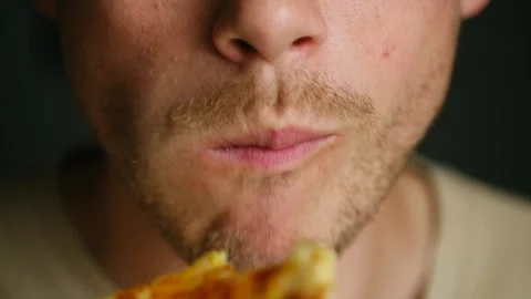 Bearded man bites off slice of cheesy pizza resting at home Stock Footage 282996283