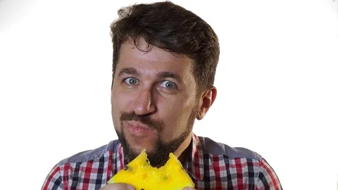 A bearded man bites a slice of juicy yellow watermelon. Stock Footage 99563139