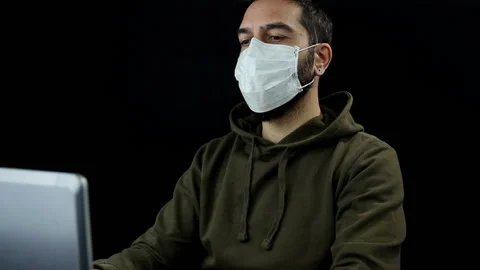 Bearded man on black background with protective medical mask works with laptop Stock Footage 144207094