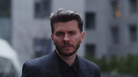 A bearded man in a black jacket looks intently into the camera. Business man Stock Footage 238844279