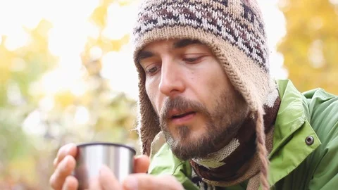 Bearded man blowing cup with tea or coffee, drinks dreams smile, autumn forest Stock-Footage 102638606