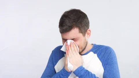 Bearded man blows his nose into tissue with eyes closed wearing shirt with blue Stock Footage 127103207